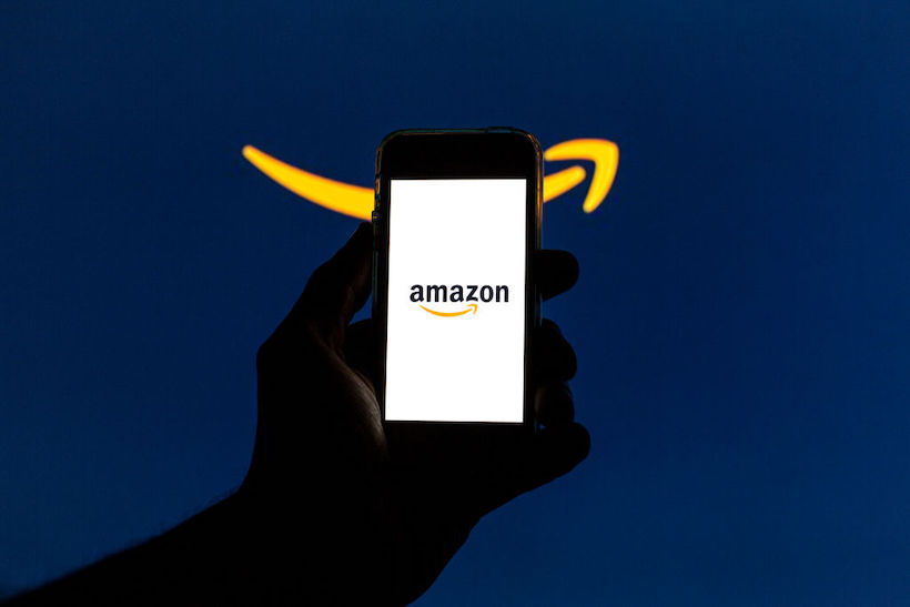 Hand holding smart phone with Amazon logo on screen