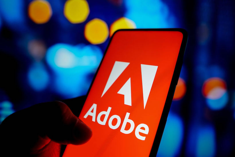 Hand holding smart phone with Adobe logo on screen