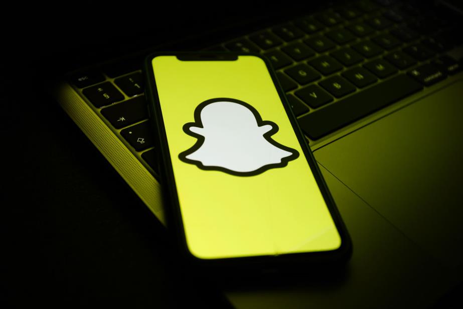 Snapchat logo displayed on a phone screen on top of a laptop keyboard