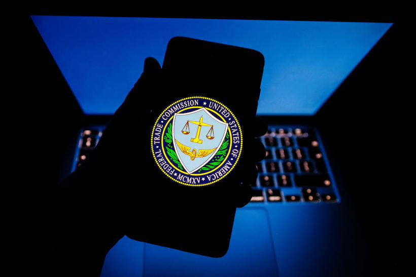 Hand holding smart phone with FTC logo on screen