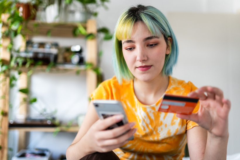 Young woman with colored hair is shopping online with a credit card